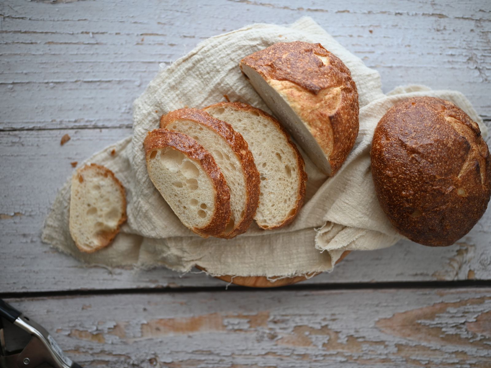 Tranches de pain au levain croustillant sur un torchon, posées sur une table en bois.