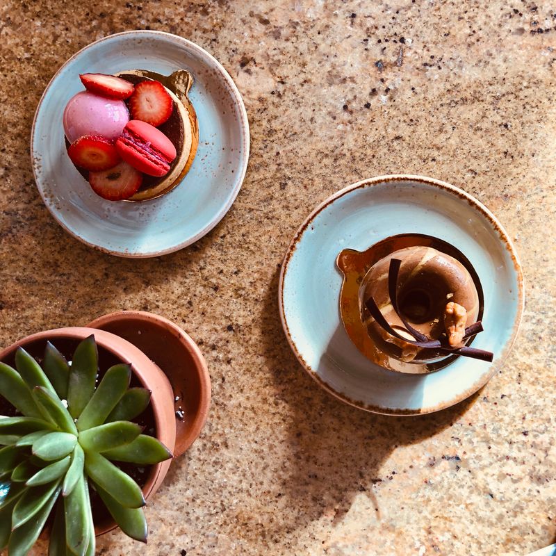 Vue de dessus de desserts gourmands avec fraises et macarons sur un plan de travail en granit.