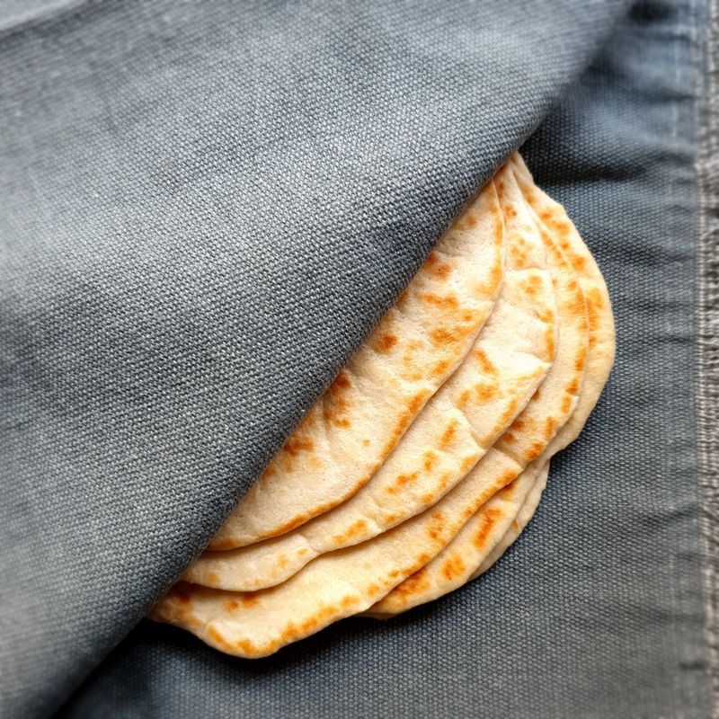 Gros plan sur des pains plats frais enveloppés dans une serviette en tissu.