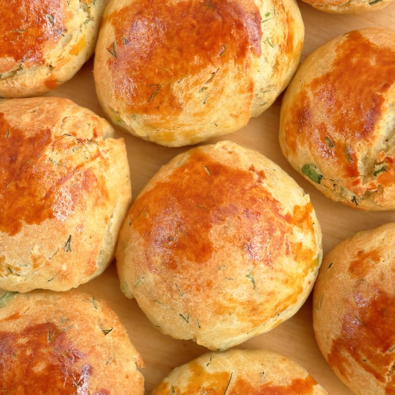 Vue du dessus de petits pains aux herbes dorés, fraîchement cuits sur une planche en bois.