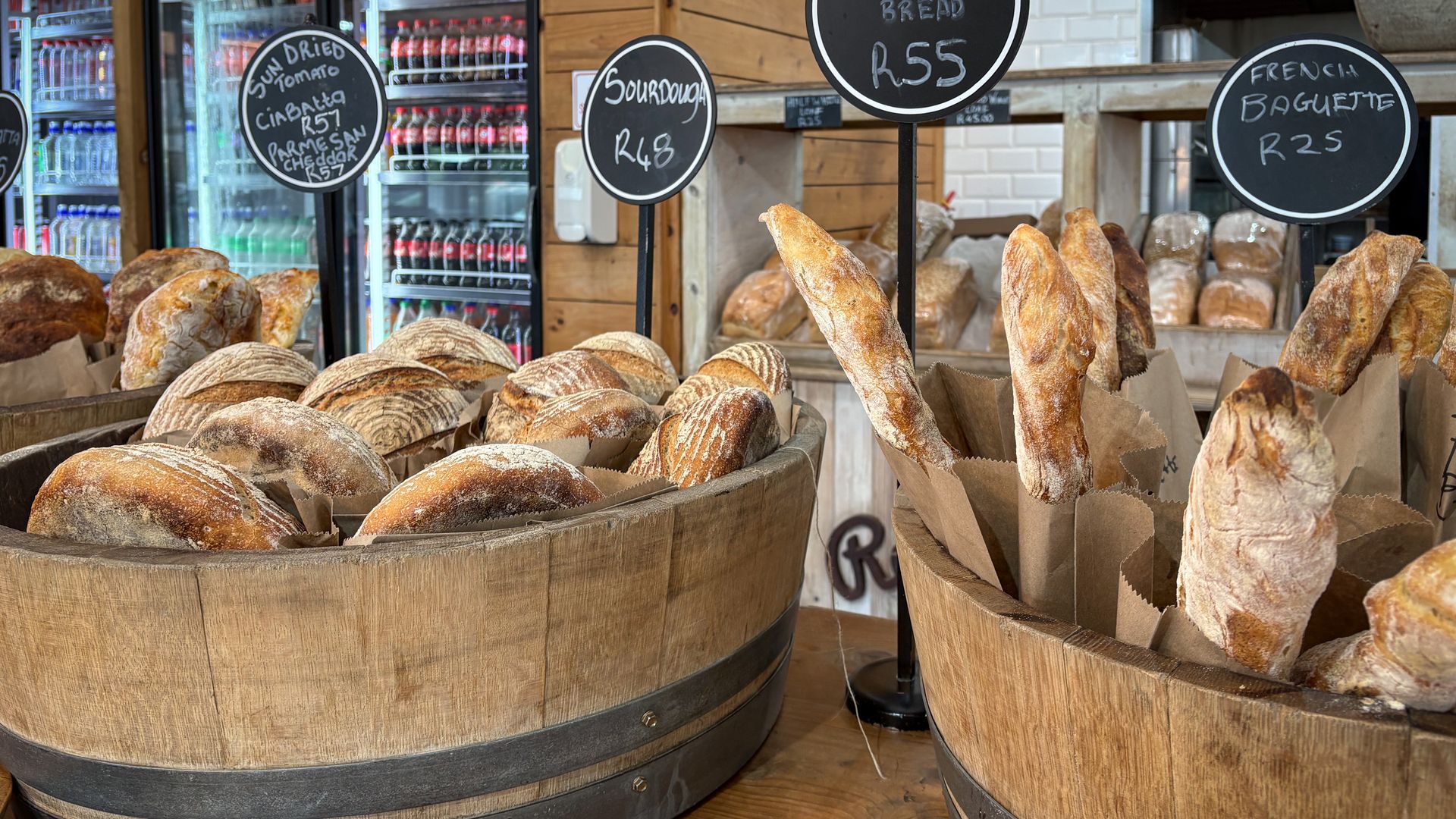 Boulangerie artisanale chaleureuse avec pains variés présentés dans des tonneaux en bois.
